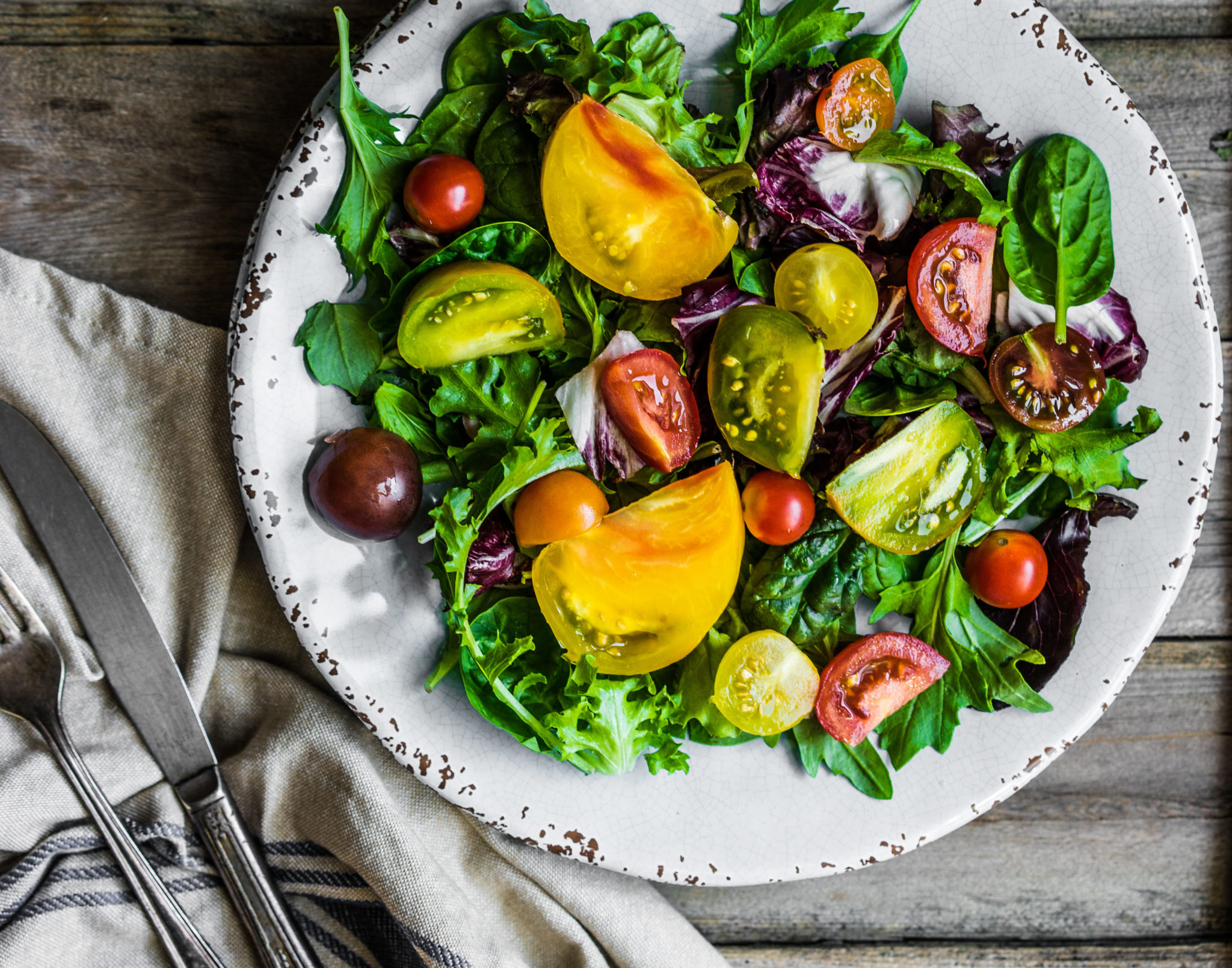 Fresh salad with spinach,arugula and heirloom tomatoes on rustic background